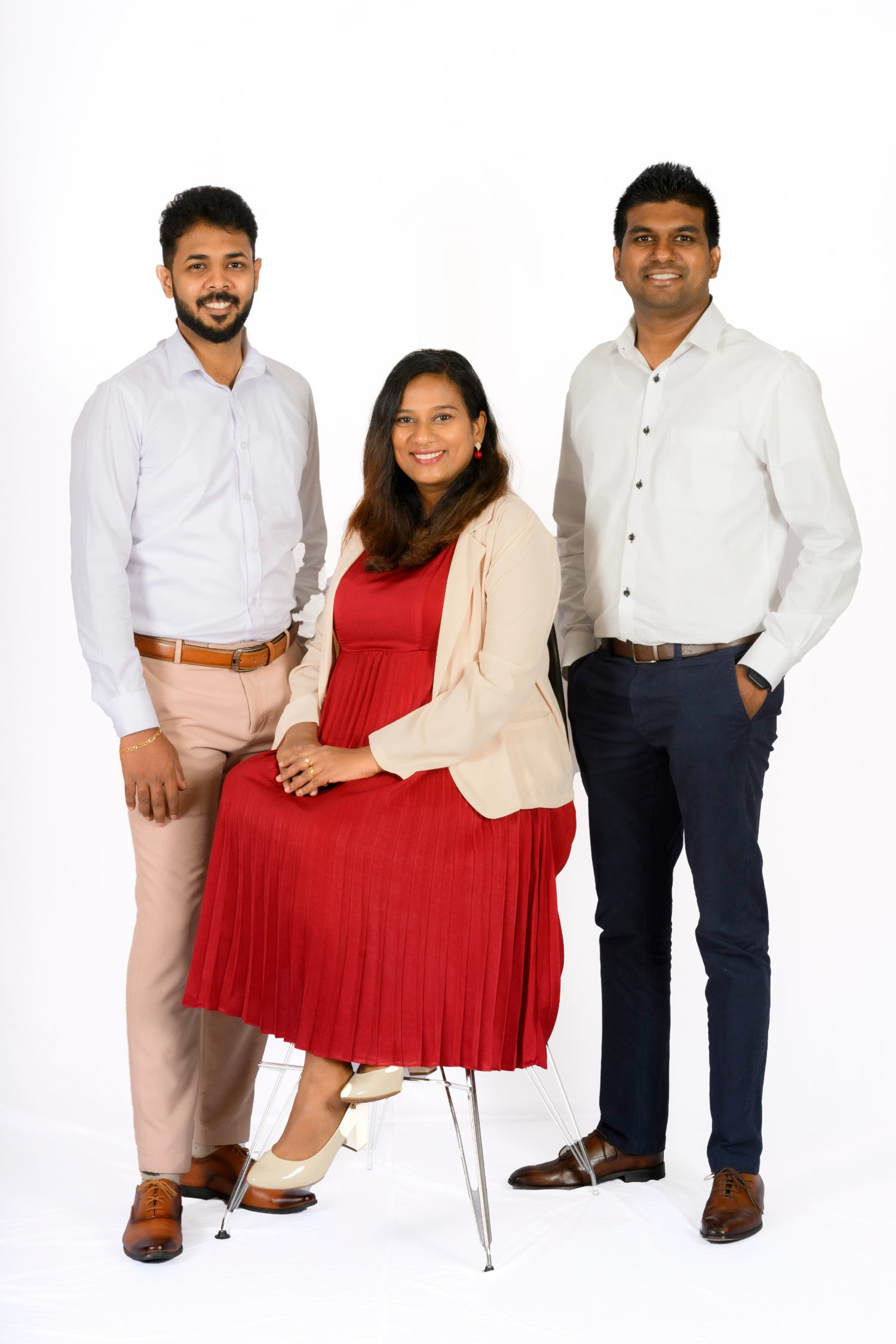 A woman in red dress sitting, two men standing.