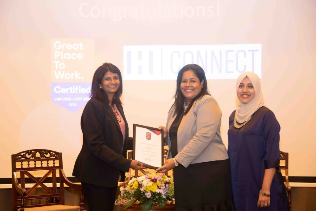 Three women smiling while holding a certificate.