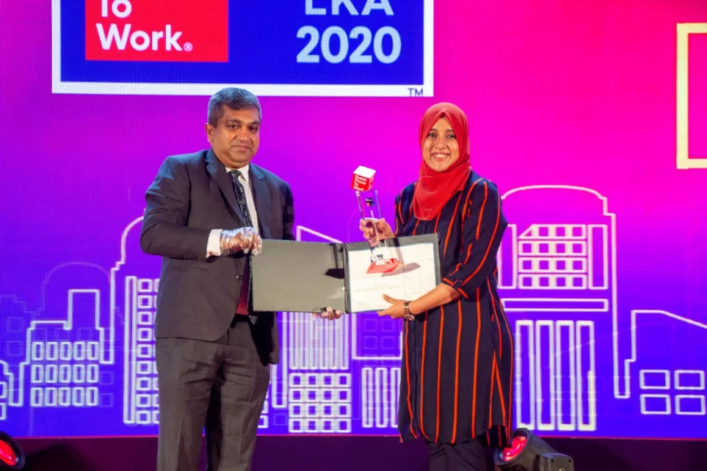 A man and woman holding awards on stage.
