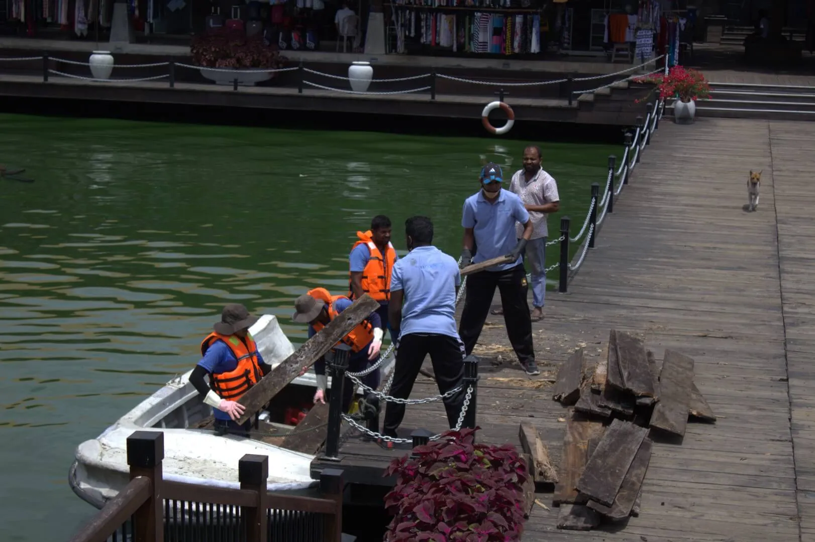 A group of people working on a wooden dock with a boat.