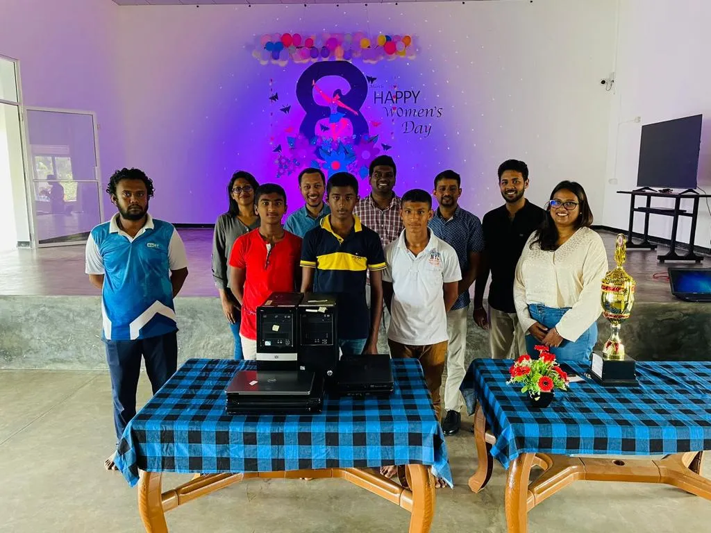 A group of people standing behind two tables displaying electronic devices.
