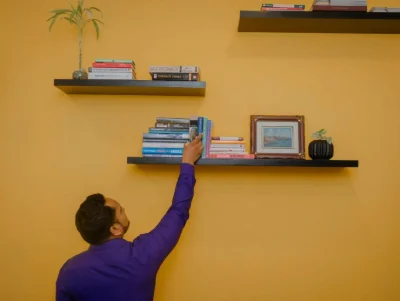 A man reaches for a book on a shelf.