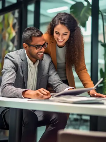 A male and female employee of H connect similing and looking at a laptop