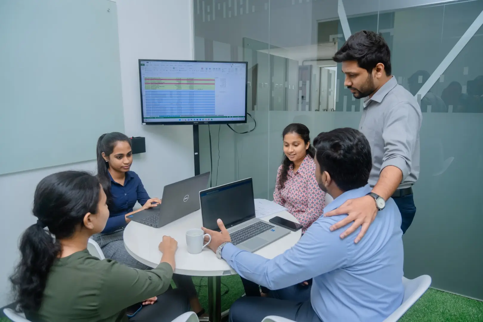 Employees of H Connect in a meeting room with Laptops